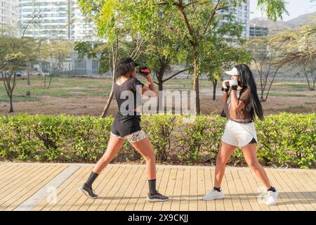 Zwei Frauen üben bei einem Fitness-Wettkampf im Freien Kampftechniken aus. Stockfoto