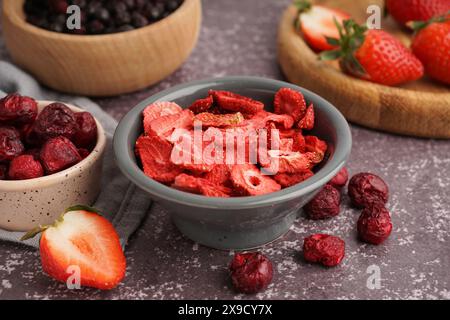 Schüssel mit gefriergetrockneten Erdbeeren und Kirschen auf grauem Hintergrund Stockfoto