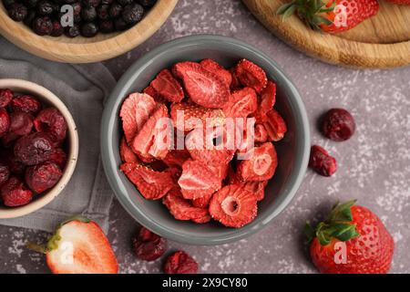 Schüssel mit gefriergetrockneten Erdbeeren und Kirschen auf grauem Hintergrund Stockfoto