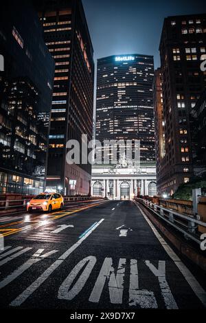 Ein gelbes Taxi auf dem Park Ave Viaduct, mit dem Grand Central Terminal und dem MetLife Building im Hintergrund - Manhattan, New York City Stockfoto