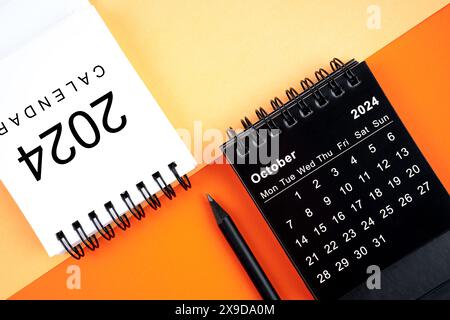 Oktober 2024 Schreibtischkalender in Schwarz-weiß-Farbe mit Bleistift auf orangefarbenem Hintergrund. Stockfoto