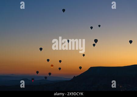 Herrlicher Sonnenaufgang mit Ballons in Kappadokien, Türkei. Wunderschöne Landschaft mit Silhouetten von Ballons bei Sonnenaufgang vor einem bezaubernden Himmelhintergrund. Stockfoto