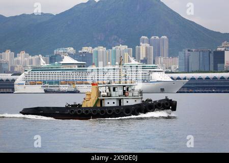 Das Kreuzfahrtschiff Voyager of the Seas liegt in Hong Kong Kai Tak Cruise Terminal & Schlepper, Royal Caribbean International Stockfoto