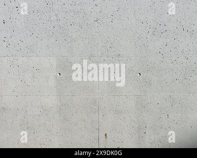 Betonhintergrundstruktur. Rohmaterial einer Gebäudewand mit Poren und Flecken. Echte leere Kulisse, fotografiert von einer Hausfassade. Stockfoto