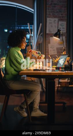 Vertikale Ansicht: Schwarze Künstlerin arbeitet in kreativer Umgebung und renoviert Sneakers, indem sie darauf zeichnet. Attraktive Frau personalisiert weiße Schuhe für Fashion Project Concept. Stockfoto