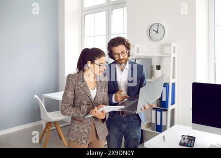 Der männliche Manager und seine Sekretärin diskutieren gemeinsam im Business-Center-Büro über Arbeitsaufgaben. Stockfoto
