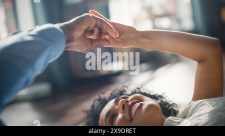 Nahaufnahme eines attraktiven Paares in Authentic Black, das während seines Aufenthalts zu Hause die Hände berührt. Freund und verliebte Freundin halten sanft die Hände. Niedliche Beziehungsinhalte. Stockfoto