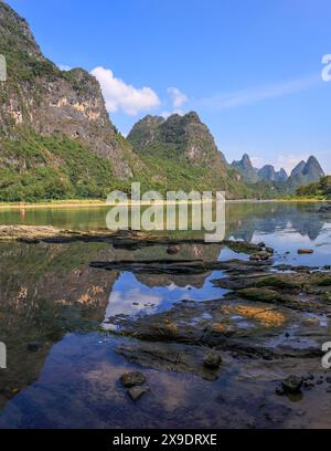 Karstgebirgslandschaft am Li-Fluss mit Reflexion und steinigem Vordergrund. Yangshuo, Guilin, Guangxi, China. Stockfoto