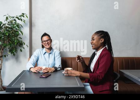 Zwei junge Geschäftsfrau-Teamarbeiter, Büroangestellte und beste Freunde, die eine Kaffeepause in Cafeteria-Eigentümern eines kleinen Unternehmens machen Stockfoto