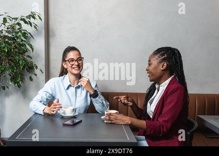 Zwei junge Geschäftsfrau-Teamarbeiter, Büroangestellte und beste Freunde, die eine Kaffeepause in Cafeteria-Eigentümern eines kleinen Unternehmens machen Stockfoto