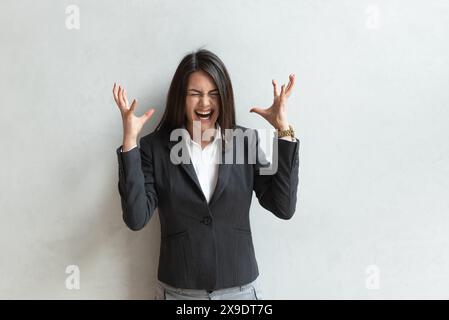 Porträt einer jungen wütenden, frustrierten Geschäftsfrau in formeller Kleidung, die im Bürogebäude steht und brüllt. Nervöse Geschäftsfrau unha Stockfoto