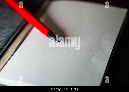 Ein offenes Notizbuch mit leeren Seiten und einem roten Stift, das auf einer Holzoberfläche liegt. Stockfoto