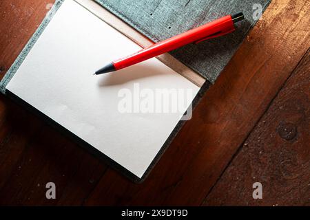 Ein offenes Notizbuch mit leeren Seiten und einem roten Stift, das auf einer Holzoberfläche liegt. Stockfoto
