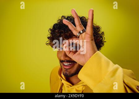 Ein hübscher junger Indianer in einem lebhaften Outfit, der mit seinen Fingern ein OK-Zeichen macht. Stockfoto