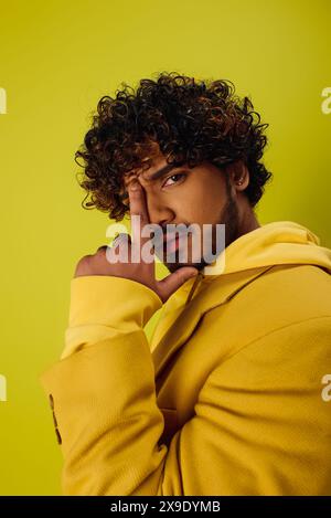 Hübscher indischer Mann in gelbem Hoodie, der vor einer lebendigen Kulisse posiert. Stockfoto