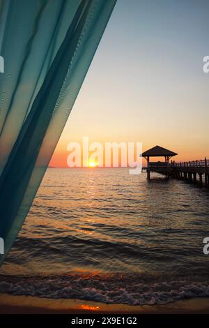 Sonnenuntergang über dem windigen Meer mit hölzernem Pier-Pavillon Stockfoto