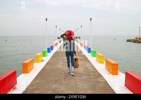 Frau in Red hat geht auf dem farbenfrohen Pier Stockfoto
