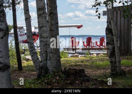 Drei rote Muskoka-Stühle auf einer Anlegestelle mit Blick auf den See Stockfoto