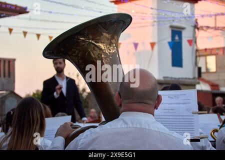 Angetränkte Blechtuba steht im Vordergrund bei einem Abendkonzert im Freien mit Musikern und Zuschauern Stockfoto