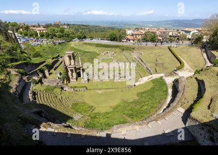 Die archäologische Stätte des römischen Theaters in der historischen mittelalterlichen Stadt Volterra in der Toskana, Italien an einem sonnigen Tag mit blauem Himmel und grünem Gras. Stockfoto