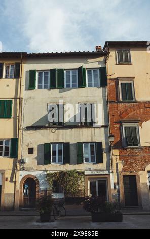 Traditionelles Apartmentgebäude in der historischen mittelalterlichen Stadt Lucca in der Toskana an einem sonnigen Tag mit blauem Himmel, Fenstern und Holzläden. Stockfoto