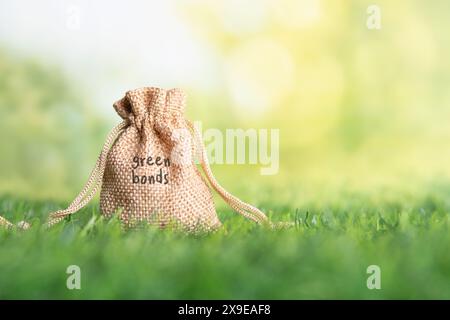 Nahaufnahme eines Jutebeutels mit den Worten „Green Bonds“ auf einem grünen Grasfeld. Umweltfreundliche Investitionen, Klimaanleihen-Konzept. Stockfoto