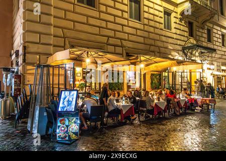 Leute, die draußen sitzen und abends in einem italienischen Restaurant essen und trinken, in Rom, Italien Stockfoto