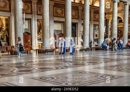 Eine Gruppe von Nonnen spaziert an den ionischen Säulen eines Seitenschiffs in der Basilika di Santa Maria Maggiore in Rom, Italien Stockfoto