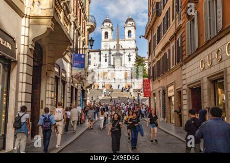 Menschen, die auf dem Weg sind Leute laufen entlang der Via dei Condotti, einer schicken Straße in Rom mit der Spanischen Treppe im Hintergrund, Rom, Italien Stockfoto