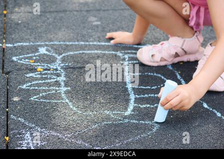 Unerkennbare Mädchenzeichnung auf dem Boden mit farbigen Kreiden. Stockfoto