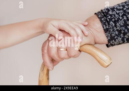 Gehbehinderungen. Nahaufnahme einer älteren behinderten Frau, die sich auf ihren Gehstock gestützt hat. Alte Frauenhände, die den Griff eines Rohrs halten. Stockfoto