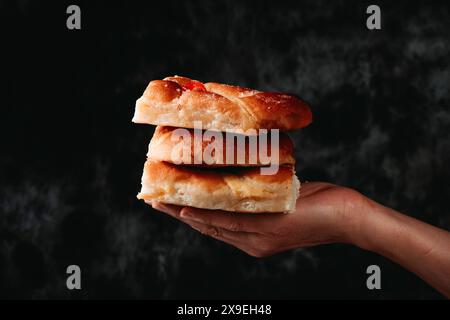 Nahaufnahme der Hand eines Mannes mit einigen Stücken katalanischer Coca de sant joan, typisch für katalonien, spanien, und traditioneller Art, die auf saint Johns Eve gegessen wurde, Stockfoto