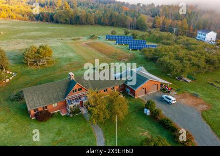 Bauernhof mit Nebengebäuden im Herbstwald unter den Wolken. Draufsicht der Drohne. New Hampshire, USA Stockfoto