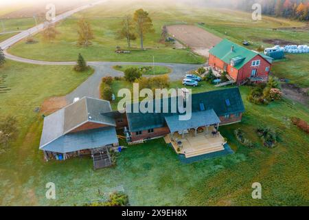 Bauernhof mit Nebengebäuden im Herbstwald unter den Wolken. Draufsicht der Drohne. New Hampshire, USA Stockfoto