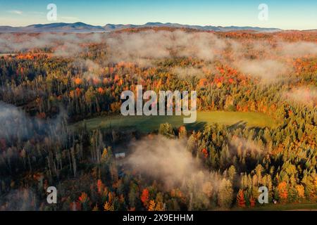 Der Herbstwald schmückt ein abgelegenes Haus unter Wolken und Bergkulisse. Drohnenansicht. New Hampshire Stockfoto