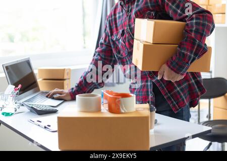 Geschäftsmann entscheidet sich, zu Hause in kleine KMU zu investieren, indem er Laptop und Smartphone verwendet, Online-Marketing durchzuführen und Dinge online über eine Anwendung zu verkaufen Stockfoto