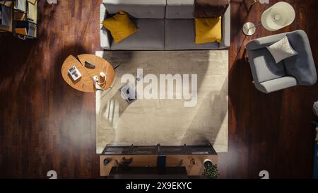 Blick von oben auf ein stilvolles Apartment mit geschmackvoll eingerichtetem Interieur, Kaffeetasse und Laptop auf dem Boden. No People konzeptionelle Aufnahme eines modernen Loft-Wohnzimmers. Platz für Home Office oder Entspannung. Stockfoto