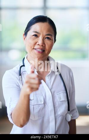 Zuversichtliche Ärztin, die in moderner Krankenhausumgebung Daumen aufgibt Stockfoto