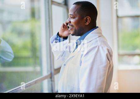Lächelnder schwarzer Arzt, der ein Telefongespräch in einem Krankenhaus führt Stockfoto