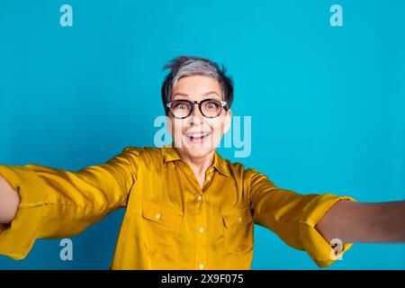 Foto von aufgeregten attraktiven Dame gekleidete Hemdbrillen, die Selfie emtpy Raum schwenken isolierte blaue Farbe Hintergrund Stockfoto