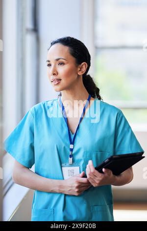 Selbstbewusste Krankenschwester, die Tablette im Krankenhausflur hält Stockfoto