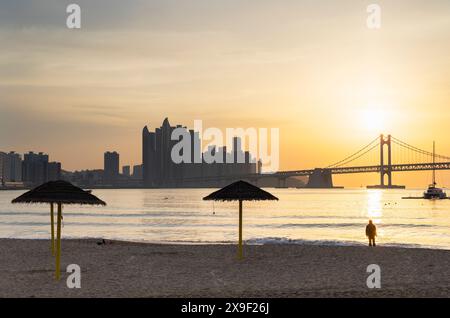 Mann am Gwangalli Beach mit Gwangan Bridge im Hintergrund bei Sonnenaufgang, Busan, Südkorea Stockfoto