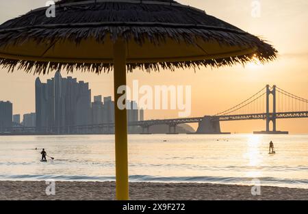 Leute paddeln am Gwangalli Beach bei Sonnenaufgang, Busan, Südkorea Stockfoto