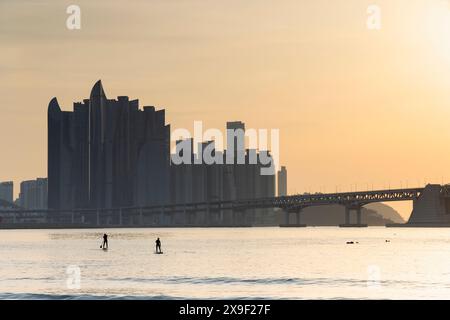 Leute paddeln am Gwangalli Beach bei Sonnenaufgang, Busan, Südkorea Stockfoto