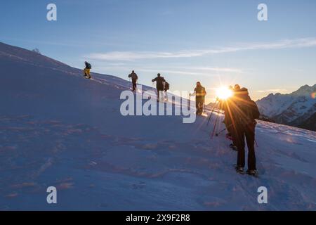 Die Gruppe der Schneeschuhe blickt auf die schneebedeckte Seite des Berges Stockfoto