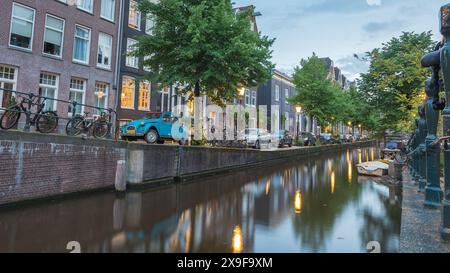 Ein alter blauer Citroen mit rotem Dach, der am 27. Mai 2024 in der Abenddämmerung auf einer Kanalseite in Amsterdam, Niederlande, geparkt wurde. Stockfoto