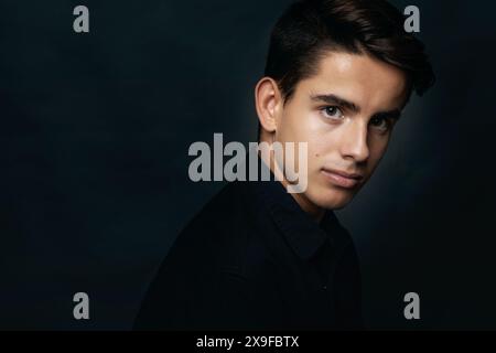 Porträt eines hübschen jungen Mannes in Schwarz vor schwarzem Hintergrund Stockfoto