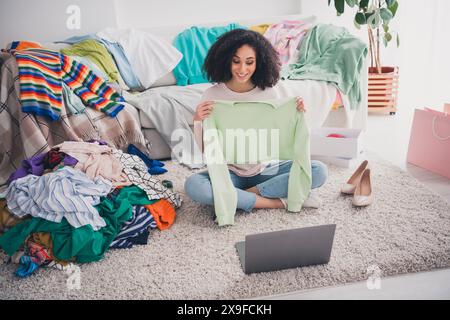 Foto eines hübschen Mädchens, das trendige Outfit trägt und im Freien Kleidung verkauft Stockfoto