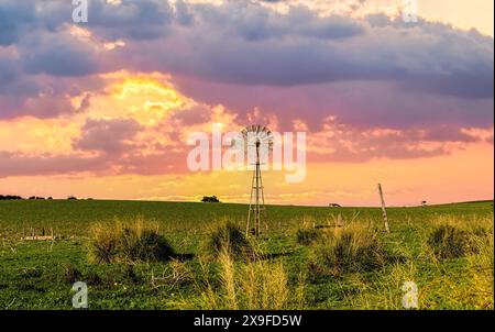 Sonnenuntergang über einer traditionellen Metallwindmühle in ländlicher Outback-Landschaft, Western Australia, Australien Stockfoto