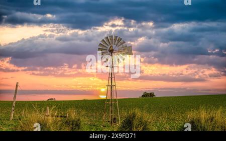 Sonnenuntergang über einer traditionellen Metallwindmühle in ländlicher Outback-Landschaft, Western Australia, Australien Stockfoto